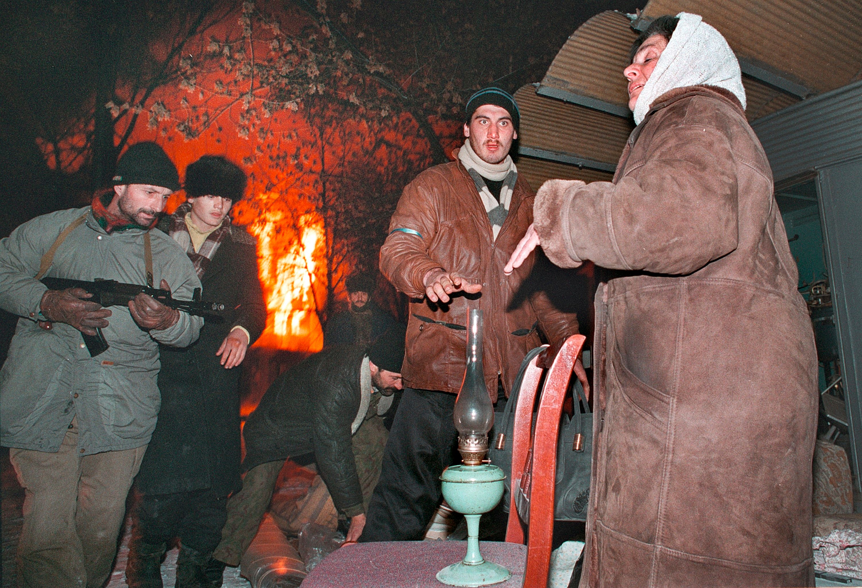 Боевики помогают женщине, которая покидает горящий Грозный. Декабрь 1994. Фото: Александр Неменов